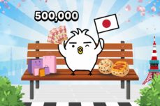 Bird Tori in the bench in front of Tokyo Tower holding a Japan Flag and surrounded by Japanese food and shopping bags