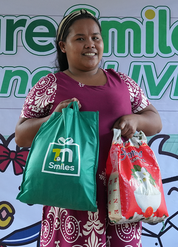 One Million Smiles 2026. A student's mother holding her One Million Smiles package and a pack of rice