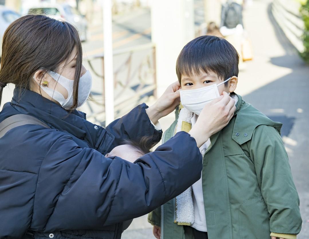 Ibu memasangkan masker ke anaknya