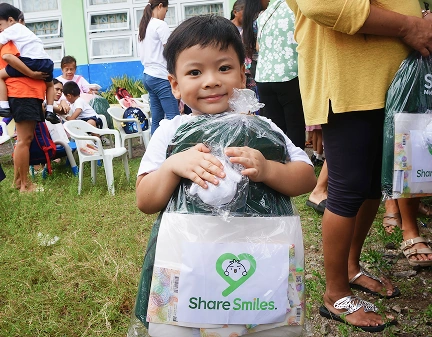 a kid holding a bag with 'Share Smiles' logo