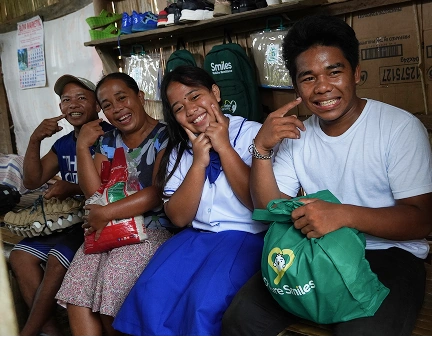 Family of four pointing finger at their smile.