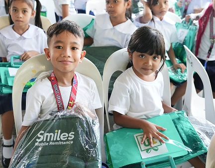 Two kids on the front post with 'smiles' logo visible on gift bags.