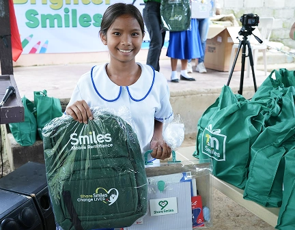 A student shows off her bag with 'smiles mobile remittance' logo.