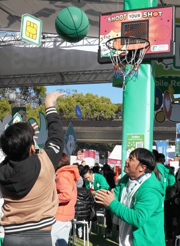 A visitor at smiles' booth throws a basketball towards a basket